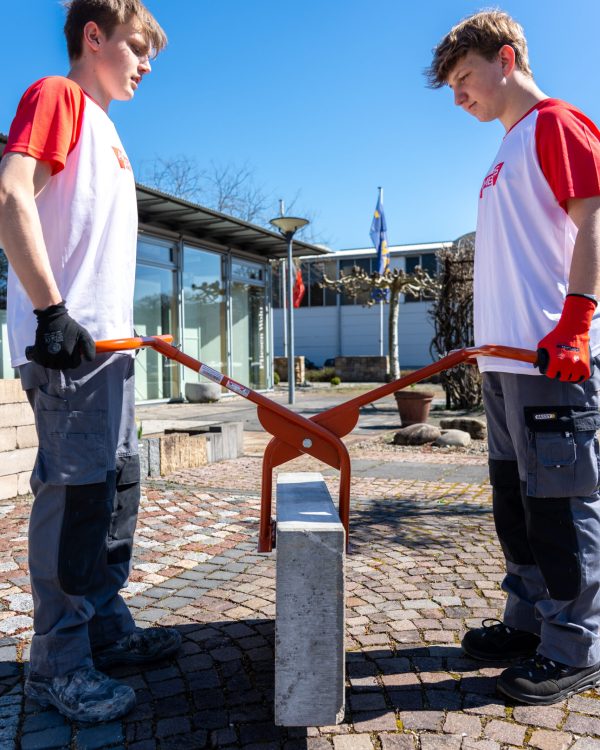 Zwei Bauarbeiter heben einen Betonstein mit einem ergonomischen Greifwerkzeug von Ambros-Technik.